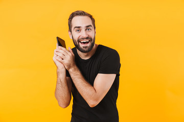 Poster - Image of brunette man wearing t-shirt rejoicing and talking on smartphone