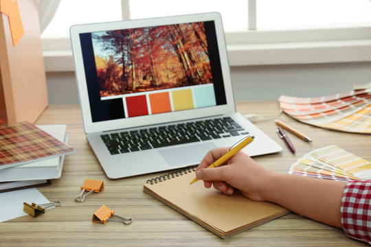 Female designer working at wooden table indoors, closeup