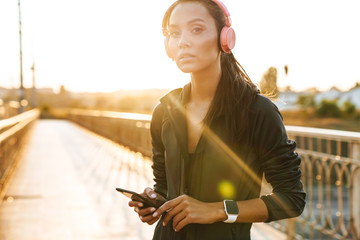 Canvas Print - Image of attractive young woman using cellphone and headphones