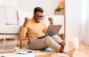 Poster - Guy Holding Laptop Shaking Fists Sitting On Floor Indoor