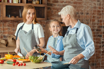 Wall Mural - Little girl happy to help mom and granny with dinner