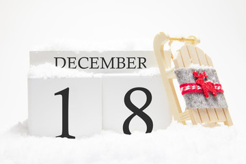 Wooden calendar for December, 18 th day of the winter month. The symbols of winter are snow and sleigh. Concept of holidays, vacation and winter fun.