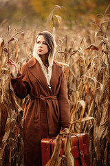 Canvas Print - Style woman in coat with suitcase on corn field in autumn time season