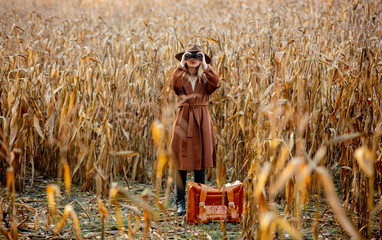 Canvas Print - Style woman with travel suitcase and binoculars on corn field in autumn time season