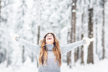 Wall Mural - Young, beautiful woman with winter cap and gray sweater and closed eyes in winter landscape