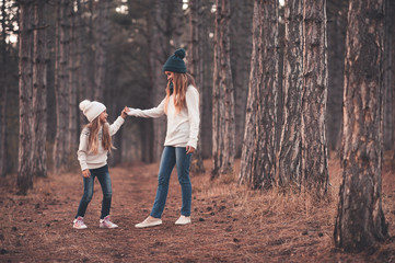 Wall Mural - Funny girls 5 and 10 year old playing outdoors in woods. Wearing warm knitted sweaters and hats. Winter season.