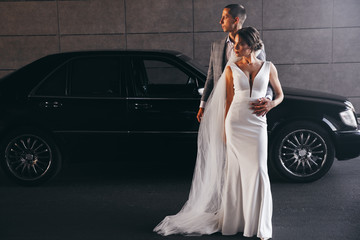 Wall Mural - wedding photo next to a black car.beautiful couple wedding photo