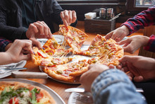 Group Of Students Friends Eat Italian Pizza, Hands Take Slices Of Pizza In A Restaurant