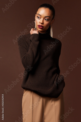 Photographie Portrait pretty fashion beauty model dark hair style beautiful sexy woman perfect cosmetic makeup mascara blush face tanned skin care wear clothes brown sweater accessory jewelry earrings