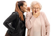 Young woman whispering to a surprised senior woman