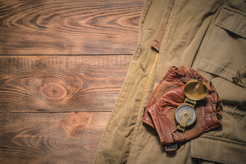 Wall Mural - Old brown jacket, gloves and compass on wooden board background.