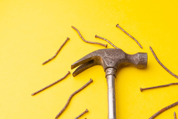 Old hammer and rusty nails. Yellow background