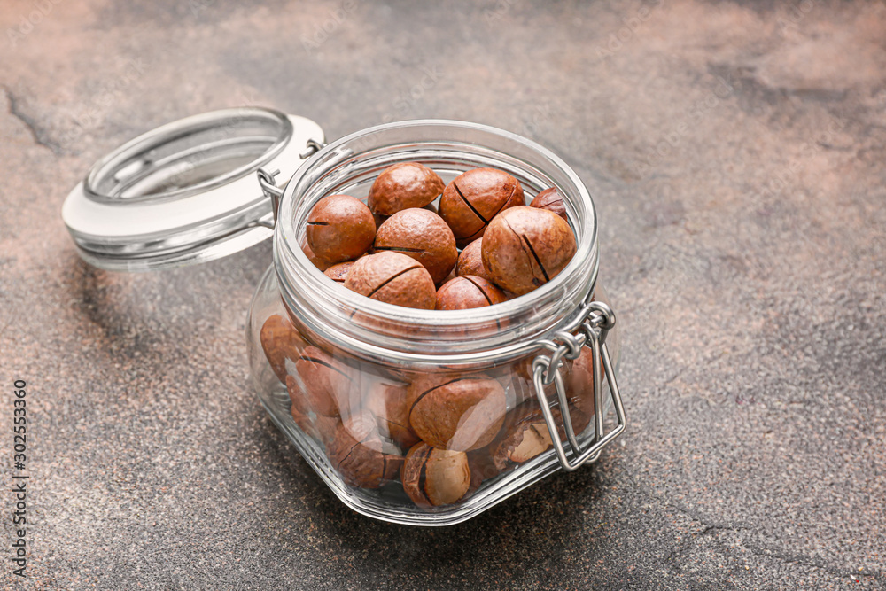Jar with macadamia nuts on grey background