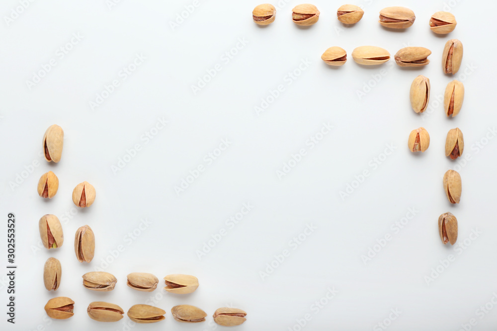 Frame made of tasty pistachio nuts on white background