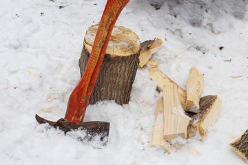 Axe and firewood on the background of snow close-up. Chop wood. The concept of alternative fuel.