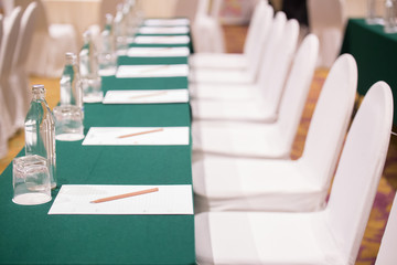 Selective focus of Paper, pencil, water bottle, glass  on the table in the seminar room background