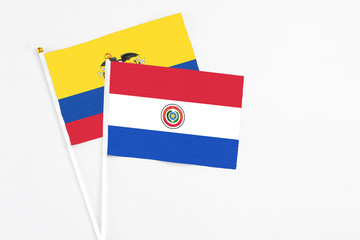 Paraguay and Ecuador stick flags on white background. High quality fabric, miniature national flag. Peaceful global concept.White floor for copy space.