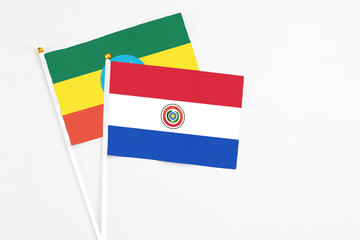 Paraguay and Ethiopia stick flags on white background. High quality fabric, miniature national flag. Peaceful global concept.White floor for copy space.