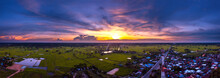 Panorama Top View Aerial Photo From Flying Drone Over Village In Thailand.Cumulus Sunset Clouds With Sun Setting Down On Dark Background.