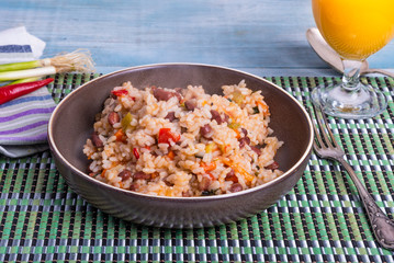 Traditional Jamaican dish - rice with beans and vegetables in a bowl and a glass of juice on a bamboo napkin, delicious vegetarian dish