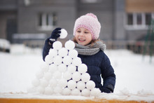 Portrait Of Cute Little Kid Girl Playing With Snowballs Outdoors, Walking And Having Fun On A Winter Day