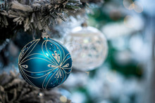 Christmas Background. Detail View Of Blue And Silver Baubles And Festive Decorations Hanging On A White Christmas Tree.