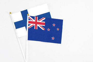 Wall Mural - New Zealand and Finland stick flags on white background. High quality fabric, miniature national flag. Peaceful global concept.White floor for copy space.