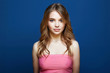 Beautiful young woman in pink dress over blue background