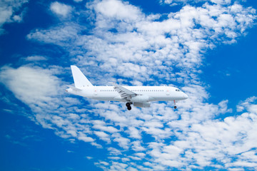 white passenger plane comes in to land with natural background of white clouds and blue sky