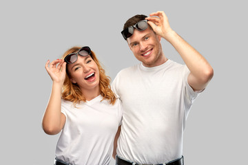 Poster - summer accessory, eyewear and people concept - portrait of happy couple in white t-shirts and sunglasses over grey background