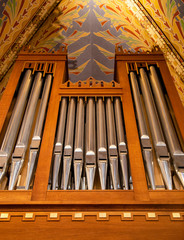 Pipe organ frontal shot, shiny silver prospect pipes pattern, row closeup. Sacral music, church musical service and classical organ concert poster concept. Old pipe organ in a small wooden church