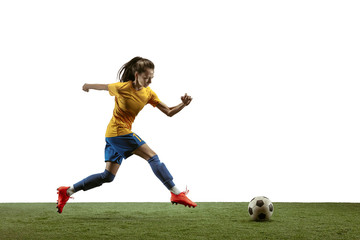 Young female soccer or football player with long hair in sportwear and boots kicking ball for the goal in jump on white background. Concept of healthy lifestyle, professional sport, motion, movement.