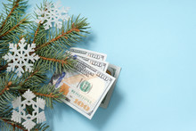 dollars and snowflakes on fir branches on blue winter background with copy space. christmas gift