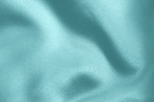 Light Blue Colored Background Of Soft Draped Fabric. Beautiful Satin Silk Textured Cloth For Making Clothes And Curtains. Elegant Textile Texture.