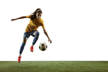 Young female soccer or football player with long hair in sportwear and boots kicking ball for the goal in jump on white background. Concept of healthy lifestyle, professional sport, motion, movement.