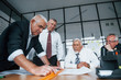 © standret - Planning construction by measuring it on paper. Aged team of elderly businessman architects have a meeting in the office