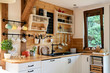 Interior of cozy wooden kitchen with window in a cottage in the country.  Vintage kitchenware and rustic decor with sink and kitchen shelves. Light indoors.