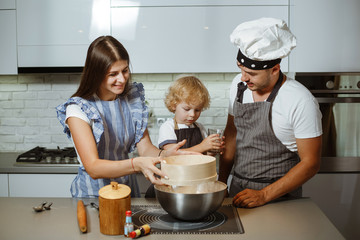 Wall Mural - Beautiful family in the kitchen together preparing a pizza.