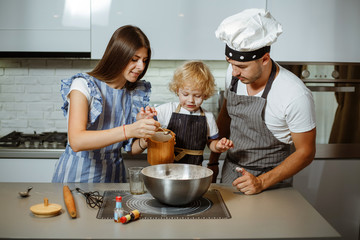 Wall Mural - Beautiful family in the kitchen together preparing a pizza.