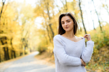 Female portrait. Young woman in casual wear posing in autumn forest with yellow leaves