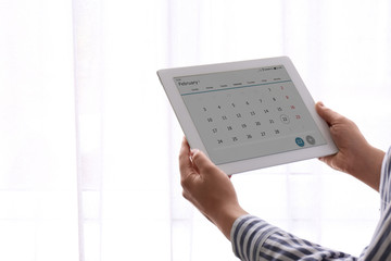 Woman using calendar app on tablet indoors, closeup