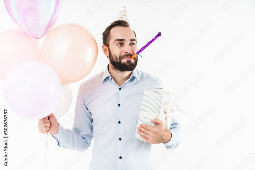 Image of man blowing party horn while holding air balloons and present box