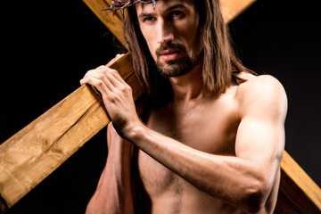 Sticker - religious and shirtless man in wreath with spikes holding wooden cross isolated on black