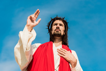 Wall Mural - low angle view of man with hand on chest gesturing against blue sky