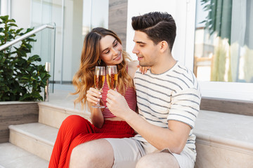 Poster - Image of young nice couple smiling and drinking wine while sitting