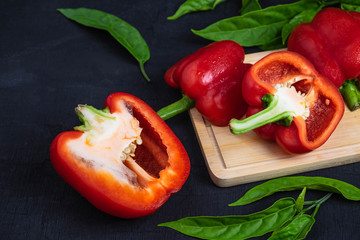 Bell pepper cut in half on a wooden cutting board on a black background.