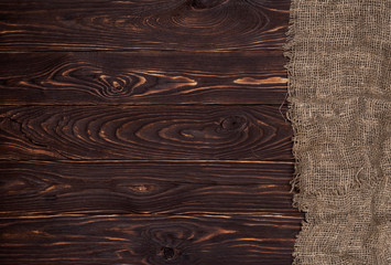 Old burlap fabric napkin on brown wooden background, top view