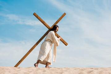 Sticker - bearded man walking with wooden cross against sky in desert