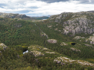 View on landscape with forest, lakes and mountain on hike to Preikestolen massive cliff famous Norway viewpoint Moody sky, autumn day. Nature and travel background, vacation and hiking holiday concept