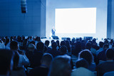 Fototapeta  - Business and Entrepreneurship concept. Speaker giving a talk in conference hall at business event. Audience at the conference hall. Focus on unrecognizable people